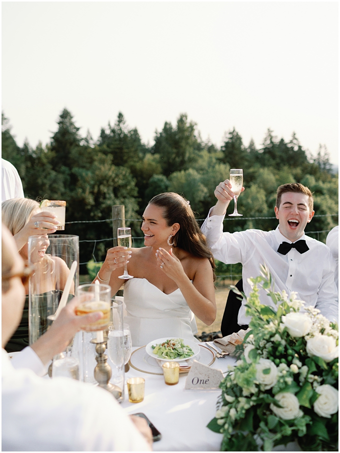 bride and groom candid laughter and cheers reacting to wedding toasts